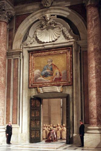 Pope John Paul II walks through the bronze Holy Door of St. Peter's Basilica at the Vatican, late Friday night, Dec. 24, 1999. (AP Photo/Andrew Medichini, File)